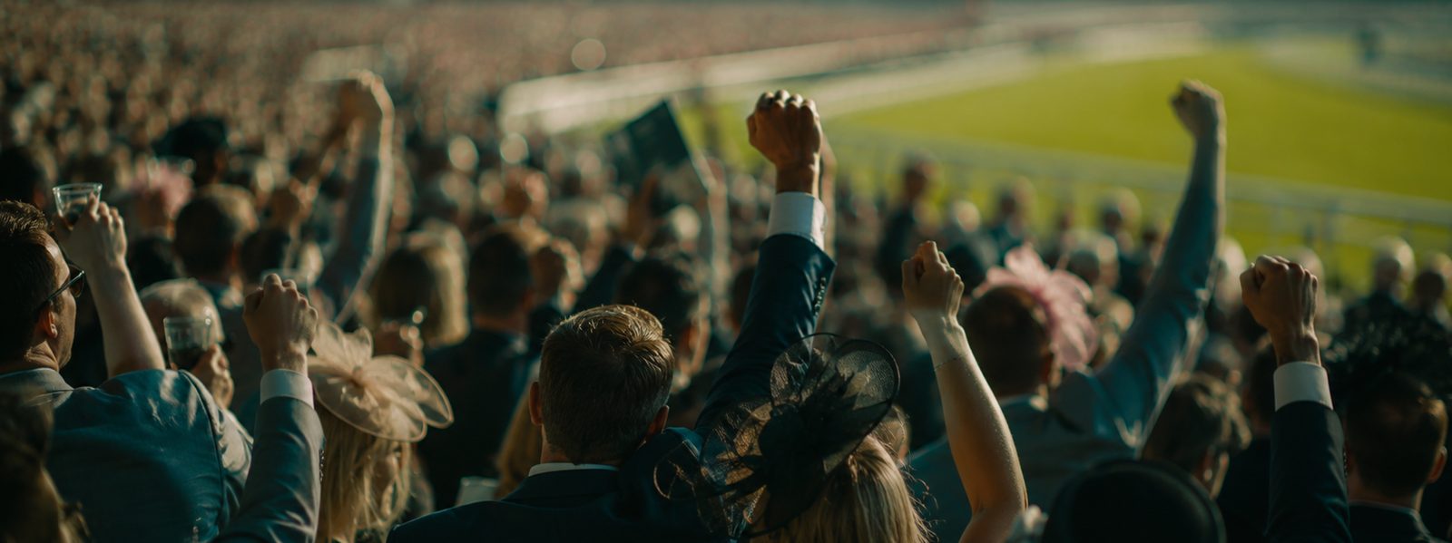 An excited racecourse crowd cheering on Grand National raceday